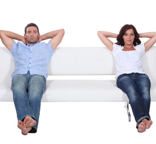 Couple sitting apart on white sofa